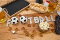 Remote control, slate, snacks, drinks and football word arranged on table