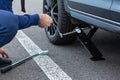 Close up of repair of a flat tire. Man lifts up a car using a jack for wheel replacement. Replacing winter and summer tires.