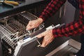 Repairing dishwasher. Close-up of man technician sitting near dishwasher Royalty Free Stock Photo
