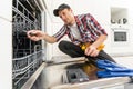 Close-up Of Repairman Fixing Dishwasher With Electric Drill Royalty Free Stock Photo