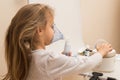 Close up. Respiratory diseases. A 5-year-old child turns on a button on the nebulizer to begin inhalation. Therapy of coronavirus Royalty Free Stock Photo