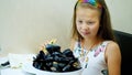 Close-up, in the restaurant, the kid girl served on the table a large bowl, a plate of cooked open blue mussels. child