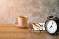 Close-up of retro alarm black clock vintage style with Blank open book, red pencil and glasses cup coffee pastel pink old Royalty Free Stock Photo