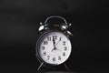 Close-up of a retro alarm clock face on a black background. Clock hands move fast, the beginning of time 12:00 AM or 12:00 PM Royalty Free Stock Photo