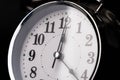 Close-up of a retro alarm clock face on a black background. Clock hands move fast, the beginning of time 12:00 AM or 12:00 PM Royalty Free Stock Photo