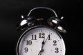 Close-up of a retro alarm clock face on a black background. Clock hands move fast, the beginning of time 12:00 AM or 12:00 PM Royalty Free Stock Photo
