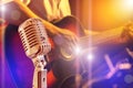 Close up retro microphone with musician playing acoustic guitar on band in night concert Royalty Free Stock Photo