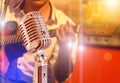 Close up retro microphone with musician playing acoustic guitar on band in night concert Royalty Free Stock Photo