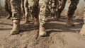 Close-up of soldiers boots marching in unison through sandy terrain