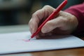 A close-up reveals a teacher's hand using a red pen to evaluate a student's test paper. The environment Royalty Free Stock Photo