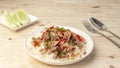 Close up Rice topped with stir-fried beef and holy basil on the wooden table with stainless spoon and fork and cucumber side dish, Royalty Free Stock Photo