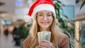 Close up rich Caucasian woman 30s lady wearing red Santa Christmas hat cap and eyeglass happy showing money dollars cash Royalty Free Stock Photo