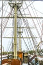 Close-up of the rigging of a wooden tall sail ship with a shiny wet wood deck against overcast sky