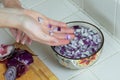 Red diced onions being dropped one handed into a bowl of water Royalty Free Stock Photo