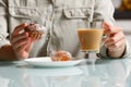 close up of right hand taking one of two curd muffins from plate, and left hand holding glass cup of coffee with milk Royalty Free Stock Photo