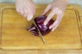Woman`s hands cutting root ends off red onion Royalty Free Stock Photo