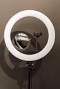 Close-up of ring LED lamp with phone holder, mirror for professional beauty blogging vlog recording on grey background.