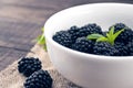 Close up of ripe blackberries in a white ceramic bowl over rustic wooden background Royalty Free Stock Photo