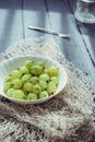 Close up ripe Green fresh gooseberry in ceramic bowl on rustic black wooden kitchen table back lightened by morning light. Farmer