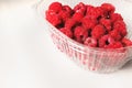 Close-up ripe juicy and delicious raspberry in a plastic transparent dish on a light background. Saturated healthy food