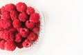 Close-up ripe juicy and delicious raspberry in a plastic transparent dish on a light background. Saturated healthy food