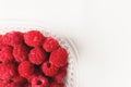 Close-up ripe juicy and delicious raspberry in a plastic transparent dish on a light background. Saturated healthy food