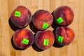 Close up of ripe peaches, carrying organic stickers, on a wooden board background