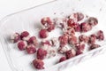 Close-up ripe red rotten raspberry with white grey mold on it. Spoiled berry in plastic box