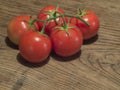 Close up ripen five red tomatoes on branch on old oak wooden tab Royalty Free Stock Photo