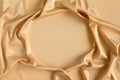 Close up of ripples in gold colored silk fabric in shape of frame. Satin textile background. Free copy space.