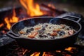 close-up of risotto cooking in cast iron pan on campfire