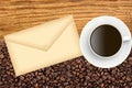 Close-up of roasted coffee beans and envelop and coffee cup
