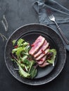 Roasted duck breast with green salad and pomegranate on black plate. Royalty Free Stock Photo