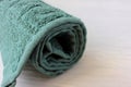 Rolled up turquoise towel on a white wooden table. Soft cotton bath towel texture. Royalty Free Stock Photo