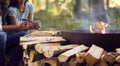 Close Up Of Romantic Couple Camping Sitting By Bonfire In Fire Bowl With Hot Drinks