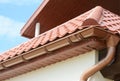 Close up on roof gutter holder and guttering downspout pipe with clay tiles roof. Installing rain gutter.