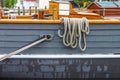 Close-up of ropes looped over the side of a vintage wooden sailing ship on a wet day with glimpses of hold harbor behind Royalty Free Stock Photo