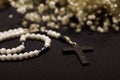 Close up of a rosary beads with blurred white small flowers, black background Royalty Free Stock Photo