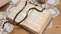 Close-up of a rosary placed on an open Bible on a table in a country cottage. Royalty Free Stock Photo