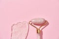 Close up of Rose quartz facial massage roller and Gua Sha scraper isolated over pink background Royalty Free Stock Photo