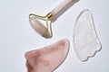 Close up of rose quartz massage roller and gua sha scrapers isolated over light background. Facial skin care at home Royalty Free Stock Photo