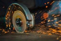 Close-up of the rotation of the disk angle grinder during operation. Bright sparks from metal cutting