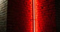 Close-up of a rough brick wall illuminated by a vertical red neon light strip Royalty Free Stock Photo
