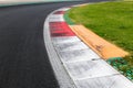 Close up of rough curb at right turn motor sport track with green field and black asphalt Royalty Free Stock Photo