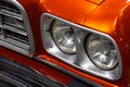 Close-up of the round headlamps of a orange american classic car. Royalty Free Stock Photo