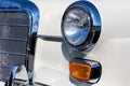 Close-up of the round headlamps and orange turn signal of a white classic car. Royalty Free Stock Photo