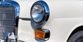 Close-up of the round headlamps and orange turn signal of a white classic car. Royalty Free Stock Photo
