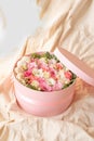 Close up of round pink box with ribbon,flowers,french macarons inside on the beige texture with open top.Florist make wedding