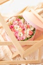 Close up of round pink box with ribbon,flowers,french macarons inside in wooden frames on the beige texture with open top