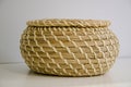 Close-up of round straw box with lid on white shelf. Eco-friendly items